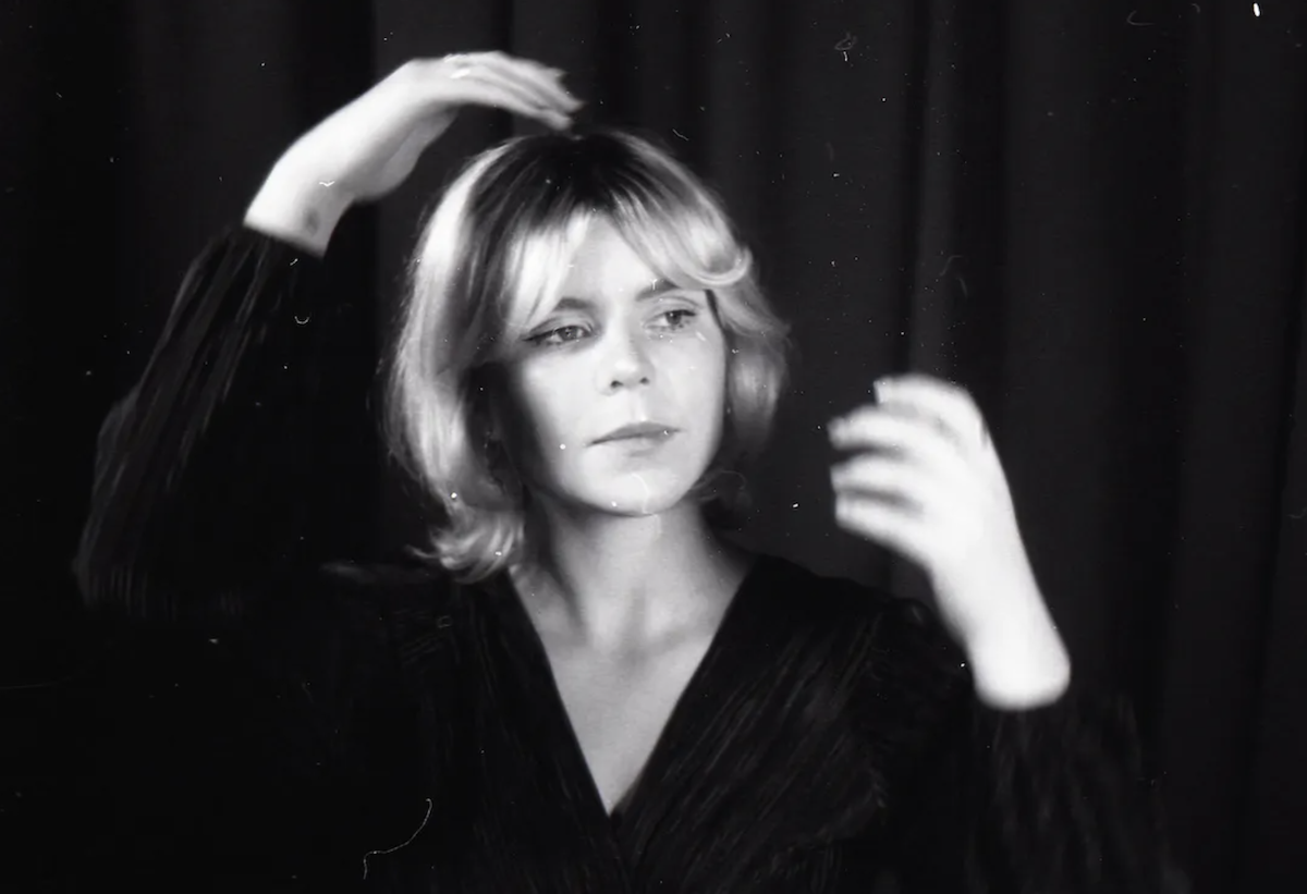 Adelaide singer-songwriter Ella Ion adjusting her hair against a dark backdrop in a grainy black-and-white promotional artist portrait photo.